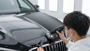 Мастер наносит глянцевую пленку на решетку авто, демонстрируя антихром черным глянцем пошаговый процесс 2026